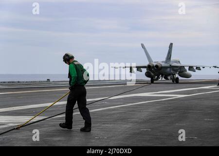 PHILIPPINISCHE SEE (19. April 2022) der Flugzeugträger Mate (Equipment) von Aviation Boatswain Landon Ross aus Hemet, Kalifornien, schiebt einen feststehenden Draht auf das Flugdeck des Flugzeugträgers USS Abraham Lincoln (CVN 72) der Nimitz-Klasse zurück. Die Abraham Lincoln Strike Group befindet sich im geplanten Einsatzgebiet der US-Flotte für 7., um die Interoperabilität durch Allianzen und Partnerschaften zu verbessern und gleichzeitig als reaktionsfähige Truppe zur Unterstützung einer freien und offenen Region im Indo-Pazifik-Raum zu dienen. (USA Navy Foto von Mass Communication Specialist 3. Class Javier Reyes) Stockfoto