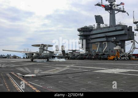 PHILIPPINE SEA (19. April 2022) ein E-2D Hawkeye, der den "Wallbangern" des Carrier Airborne Early Warning Squadron (VAW) 117 zugewiesen wurde, landet auf dem Flugdeck des Flugzeugträgers USS Abraham Lincoln (CVN 72) der Nimitz-Klasse verhaftet. Die Abraham Lincoln Strike Group befindet sich im geplanten Einsatzgebiet der US-Flotte für 7., um die Interoperabilität durch Allianzen und Partnerschaften zu verbessern und gleichzeitig als reaktionsfähige Truppe zur Unterstützung einer freien und offenen Region im Indo-Pazifik-Raum zu dienen. (USA Navy Foto von Mass Communication Specialist 3. Class Javier Reyes) Stockfoto