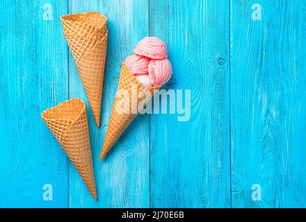 Erdbeereis und Waffelkegel auf blauem Hintergrund. Stockfoto