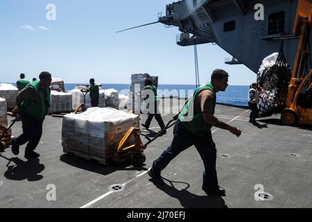 PHILIPPINISCHE SEEFAHRER (29. April 2022) transportieren Fracht in der Hangarbucht an Bord des Flugzeugträgers USS Abraham Lincoln (CVN 72) der Nimitz-Klasse während einer Auffüllung auf See mit dem Militärschiff Sea Lift Command Dry Cargo und Munitionsschiff USNS Cesar Chavez (T-AKE 14). Die Abraham Lincoln Strike Group befindet sich im geplanten Einsatzgebiet der US-Flotte für 7., um die Interoperabilität durch Allianzen und Partnerschaften zu verbessern und gleichzeitig als reaktionsfähige Truppe zur Unterstützung einer freien und offenen Region im Indo-Pazifik-Raum zu dienen. (USA Navy Foto von Mass Communication Specialist 3. Klasse Thaddeus Berry) Stockfoto