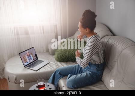 Seitenansicht einer fröhlich lächelnden Frau, die online im Video-Chat mit älteren Frauen spricht Stockfoto