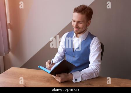 Portrait Business focused selbstbewusst fokussiert intellektuellen Spezialisten in lebhaften Experten, bärtigen jungen Mann im Hemd im Büro Schreiben von Informationen für Notizblock. Arbeitsmomente erfolgreicher kaukasischer Kerl Stockfoto