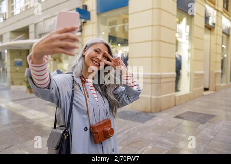 Attraktive reife Frau mit Smartphone auf der Stadtstraße Stockfoto