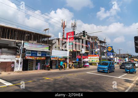 Malabe, Sri Lanka - 4. Dezember 2021: Blick auf die Straße mit Autos, Motorroller und Tuk Tuks. Gewöhnliche Menschen gehen die Straße entlang Stockfoto