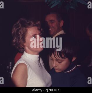 Frau mit einem aufgeschreckt Ausdruck auf einer Party mit einem lächelnden Kerl im Hintergrund. c1966 Foto von Tony Henshaw Archive Stockfoto