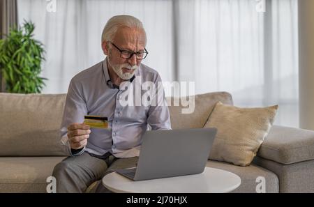 Durchdacht Senior Profi Analyse Kreditkarte, Geschäftsmann, der Online-Zahlung über Laptop, Er trägt Formalien im Büro. Stockfoto