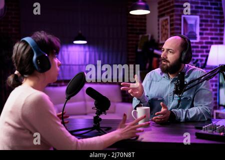 Mann und Frau erstellen Podcast-Inhalte online mit Geräten, aufzeichnen Social-Media-Diskussion. Team von Influencern, die über Lifestyle und Internetkanal im Live-Broadcast sprechen. Stockfoto