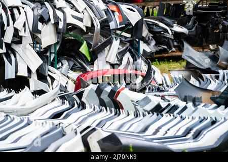 Stapel von gebrauchten vorderen Stoßfängern, hinteren Stoßfängern und Spoiler des Autos für das Recycling. Autoprodukte aus Kohlefaser, PU und PP-Kunststoff. Automobilindustrie. Stockfoto