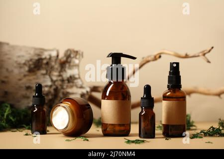 Set aus Kosmetikflaschen aus Bernstein-Glas mit Birkenrinde, Holzzweig, grünem Moos. Natürliche organische Beauty-Produkte Verpackungsdesign Stockfoto