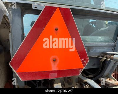 Augusta, GA USA - 04 13 22: Kubota roter Traktor orangefarbenes Warndreieck Stockfoto