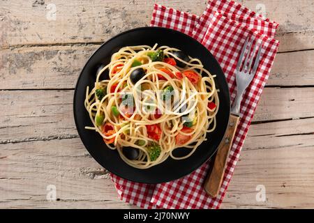 Spaghetti mit Gemüse (Brokkoli, Tomaten, Paprika) auf Holztisch Stockfoto