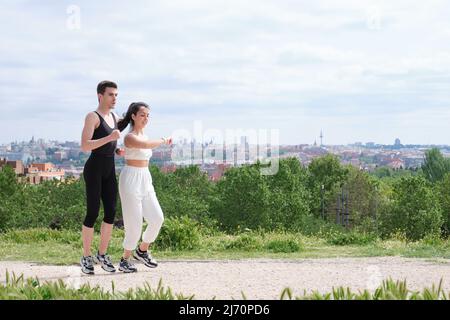 Junges, sportliches Paar, das im Freien auf der Smartwatch läuft und die Smartwatch überprüft. Stockfoto