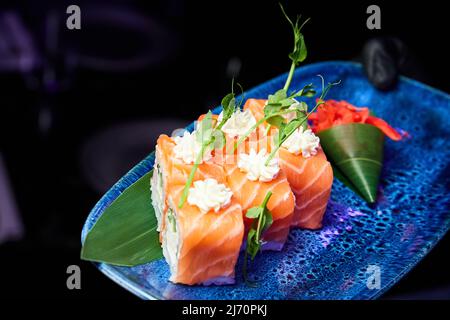 Rollen Sie Philadelphia mit Reis, Nori, Gurken, grünen Zwiebeln, Frischkäse, Lachs Stockfoto