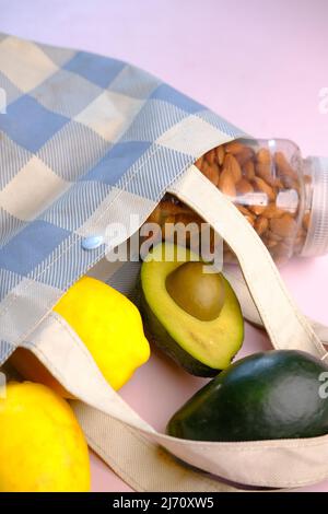 Frische Orangenfrüchte und Avocado in einer Einkaufstasche vor schwarzem Hintergrund Stockfoto