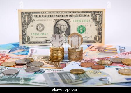 Rubel und Euro gegenüber dem Dollar. Ein Stapel von Rubel-Münzen und Euro-Münzen auf dem Hintergrund eines US-Dollars Stockfoto