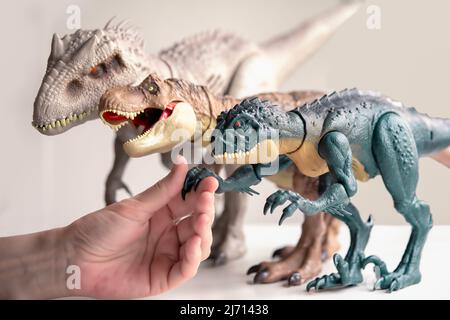 Handschlag mit Dinosauriern. Hand berührt Dinosaurier-Spielzeug. Stockfoto