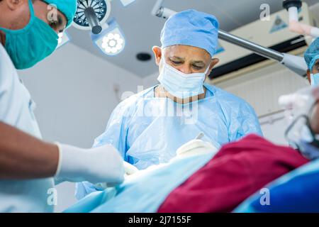 Konzentrierter Chirurg, der mit der Operation an kranken Patienten im Operationssaal beschäftigt ist - Konzept der Fachkompetenz, der spezialisierten und professionellen Behandlung Stockfoto