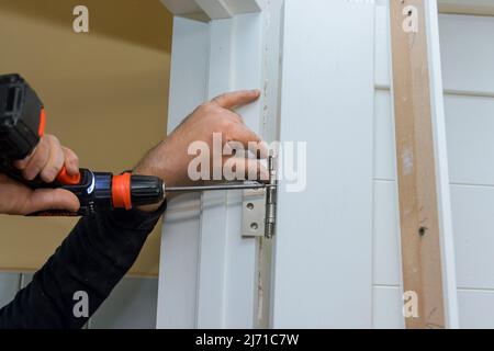 Nahaufnahme des Zimmermanns Verfahren der Hände Schrauben Scharnier auf einer Tür mit Schraubendreher Stockfoto