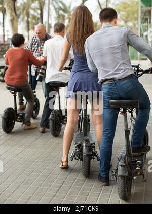 Freunde von Touristen verschiedener Generationen genießen eine Fahrt mit Elektrorollern Stockfoto