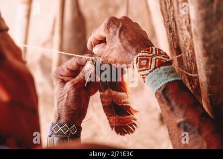 Ein indischer Mann, der einen Kokaberaufschmuck aus Federn basteln soll. Rio Xingu, September 2010. Stockfoto