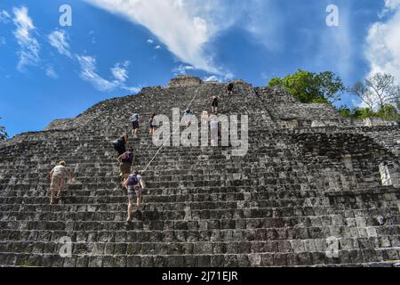 Eine Gruppe von Touristen klettert in Becán auf eine hohe Maya-Pyramide Stockfoto