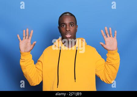 Ein junger attraktiver Mann, der überrascht und isoliert auf blauem Hintergrund aussieht Stockfoto