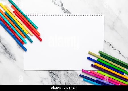 Skizzenbuch mit weißem, leerem Papier öffnen. Modell. Farbige Zeichnungsmarkierungen zum Zeichnen auf einem Marmorhintergrund. Flache Lay-Komposition. Platz für Text Stockfoto