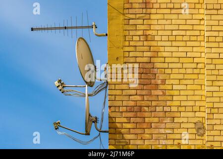 TV-Antenne und Satelliten-Parabolantennen an der Wand des Hauses befestigt. Stockfoto