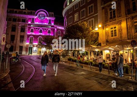 Fußgänger, die nachts vor dem Teatro da Trindade, Lissabon, Portugal, spazieren gehen Stockfoto