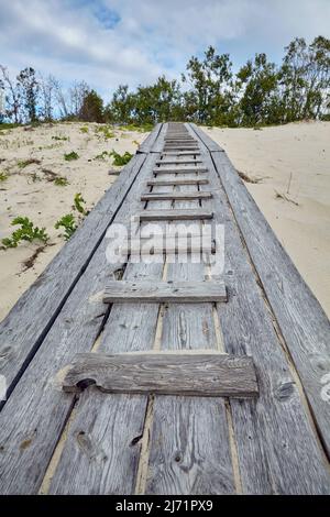 Landschaftlich schöner Holzsteg zum Meer in den Dünen. Ostsee. Stockfoto