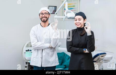 Porträt der Zahnärztin und ihrer Assistentin im Büro, Zahnärztin und ihrer Assistentin Daumen hoch, orale Profis Porträt Stockfoto