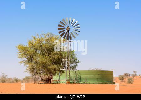 Windturbine (Windmühle) und Wasserspeicher zur Gewinnung von Grundwasser aus unterirdischen Grundwasserleitern mittels Bohrlöchern, Kalahari-Wüste, Namibia, Afrika ... Stockfoto