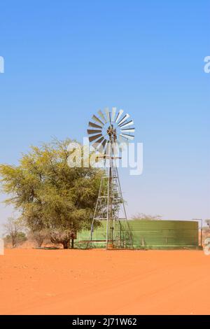 Windturbine (Windmühle) und Wasserspeicher zur Gewinnung von Grundwasser aus unterirdischen Grundwasserleitern mittels Bohrlöchern, Kalahari-Wüste, Namibia, Afrika ... Stockfoto