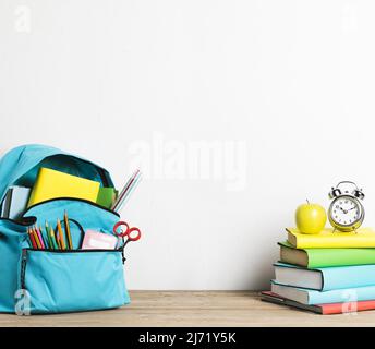 Wecker stapelt Bücher gut verpackte Schultasche mit Vorräten Stockfoto