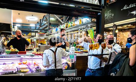 Kellner mit Gesichtsmasken servieren Bier auf dem Markt La Picatería - Mercado San Agustín - St. Agustin. Granada, Andalusien, Spanien Stockfoto