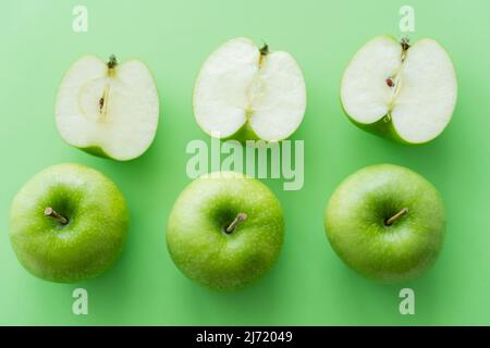 Flache Lay von leckeren ganzen und schneiden Äpfel auf grün Stockfoto