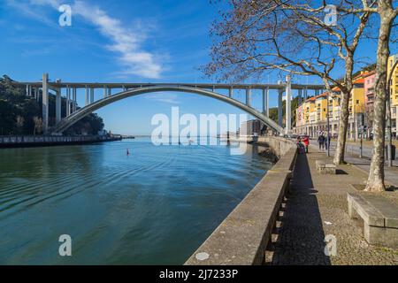 PORTO, PORTUGAL - März 5. 2022: Touristen und Einheimische genießen einen schönen frühen Frühlingstag am Douro-Fluss und der Arrabida-Brücke in Porto C Stockfoto
