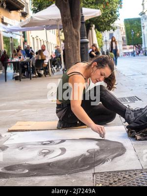 Andalusische Straßenmalerin, die auf einem Gehsteig auf einem Bürgersteig ein Frauenporträt malt, Sevilla, Andalusien, Spanien Stockfoto