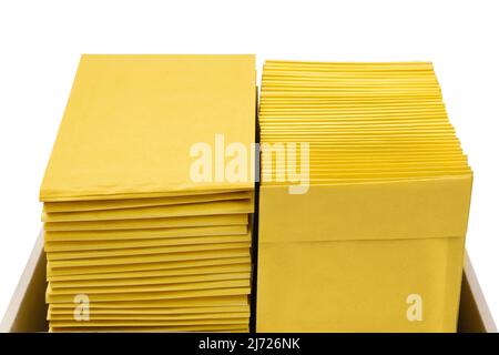 Zwei Stapel gelber Umschläge in einem Versandkarton, Draufsicht. Stockfoto