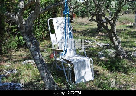 Klappstuhl Camping befindet sich im Garten auf dem Rasen an einem sonnigen Sommertag. Alten Sommer Campingstuhl. Stockfoto