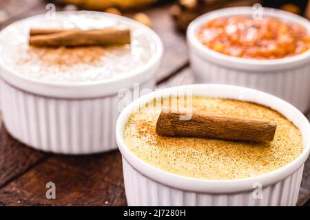 Typische brasilianische Süßigkeiten von Juni-Festen, curau, Mugunzá oder Hominy, süßer Reis oder oder Canjica, Kürbisbonbons Stockfoto