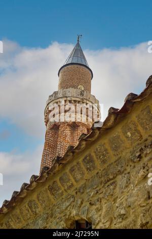 Altes Minarett einer islamischen Moschee hinter Mauern mit blauem Himmel oder weißen Wolken Landschaft, kreative Ansicht Stadt Foto Konzept Idee. Stockfoto
