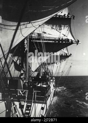 An Bord Eines Windjammers -- Mitglieder der Crew Takelage wurde von einem Rettungsboot genommen, das speziell für den Fotografen von der Seite ausgebracht wurde. Spezialfoto an Bord der Viermaster-Barke Abraham Rydberg, Sieger des Rennens aus Australien, als sie von Falmouth aus die Segel setzte, um ihre Reise nach Ipswish zu beenden. 7.Mai 1934. (Foto von London News Agency Photos Ltd.) Stockfoto