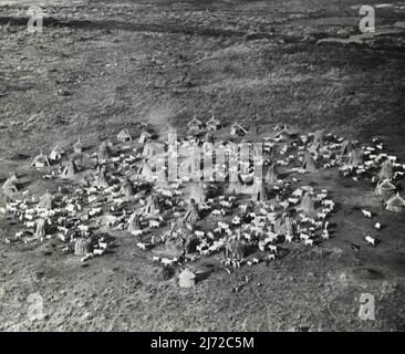 Ein primitives afrikanisches Dorf ist erstaunt über sein erstes Flugzeug südlich von Ägypten und westlich von Abessinien im tropischen Afrika liegt der anglo-ägyptische Sudan, der gelegentlich mit Stroh- und Holzhütten-Dörfern wie diesem übersät ist. Diese airview, die von dem ersten Flugzeug genommen wurde, das jemals in dem primitiven Dorf landete, bietet eine bemerkenswerte Studie über das Gemeinschaftsleben im Südsudan, das gemeinsam von England und Ägypten regiert wird. Eine wichtige Branche in diesem Bereich ist, wie das Bild betont, die Viehzucht. Die wichtigsten landwirtschaftlichen Nutzpflanzen sind Baumwolle, Weizen und Durra, ein Sorghum-Getreide, das ein Grundnahrungsmittel der Sudanesen ist. Der Sudan ist auch ein Princ Stockfoto