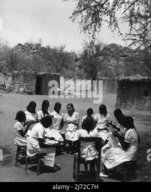 Sudanesische Mädchen Trainieren Als Lehrer. Sie Lernen In Den Klassenzimmern Von Grass Hut, Bis Das Neue College Fertig Ist. Die Nähklasse sitzt in einem Kreis um den Lehrer vor den Grashütten, die als temporäre Klassenräume aufgemacht wurden. Diese Hütten oder Tukls werden von Sudanesen in wenigen Stunden errichtet. 14.Mai 1953. (Foto von der Zentrale für Information). Stockfoto