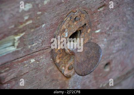 Ein altes rosafarbenes Schloss in einer braunen Holztür.Rustige Tür.Schlüsselloch. Stockfoto