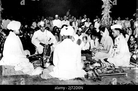 Nehrus Nichte heiratete -- die Braut und der Bräutigam (rechts), mit Blumen und Juwelen geschmückt, machen während ihrer Hochzeitszeremonie ihr Versprechen vor Agni (Feuer). Chandralekha Pandit, Tochter von Frau Vijaya Lakshmi Pandit und Nichte des indischen Premierministers Pandit Nehru, war im April 14 mit Herrn Ashok Mehta, dem indischen Generalkonsul in Saigon, in Neu-Delhi, Indien, verheiratet. An der Trauung nahmen der Generalgouverneur von Indien, Mitglieder des Kabinetts, das Diplomatische Korps und andere angesehene Persönlichkeiten Teil. 01.Mai 1949. (Foto von Associated Press Photo) Stockfoto