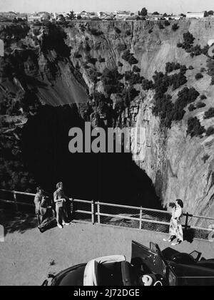 The Big Hole, Kimberley, Südafrika - Kimberley, das berühmte Diamantenzentrum Südafrikas, hat eine einzigartige Touristenattraktion in Form einer stillgewordenen Diamantenmine, die im Volksmund als „The Big Hole“ bekannt ist. Hier gruben die frühen Bagger, die im Freien mit primitiver Ausrüstung arbeiteten, einen gigantischem Krater aus, der 1.500 Fuß hoch und 1000 Fuß tief war. Moderne Abbaumethoden erweiterten später die Tiefe des Big Hole auf 4.000 Fuß, was während seiner Lebensdauer 15 Millionen Karat Diamanten im Wert von über 47.000.000 £ergab. Kimberley liegt 300 Meilen südwestlich von Johannesburg, dem südafrikanischen Terminal von Qantas. Oktober 10 Stockfoto