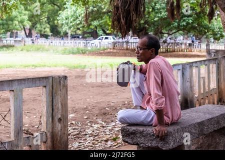 Vellore, Tamil Nadu, Indien - 2018. September: Ein indischer Mann mit Brille sitzt allein auf einer Parkbank. Stockfoto