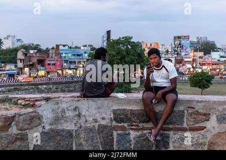 Vellore, Tamil Nadu, Indien - 2018. September: Ein indischer Junge sitzt mit seinem Telefon auf den Wällen des Vellore Fort Komplexes. Stockfoto